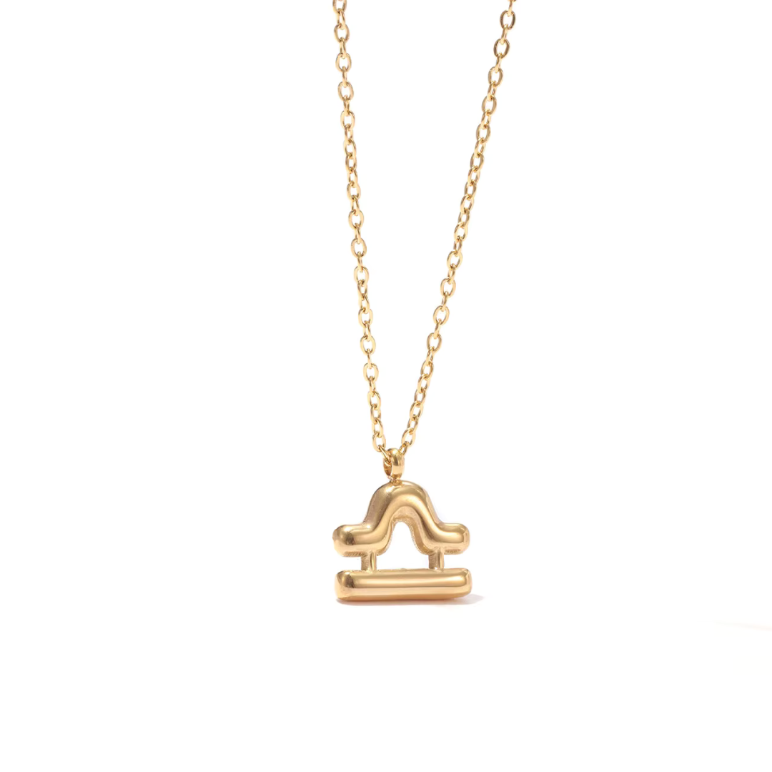All 12 zodiac symbol bubble necklaces in 18K gold PVD displayed on a stone surface. Bold, chunky glyph pendants on delicate cable chains — waterproof and tarnish-free.