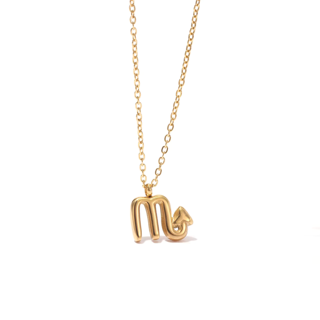 All 12 zodiac symbol bubble necklaces in 18K gold PVD displayed on a stone surface. Bold, chunky glyph pendants on delicate cable chains — waterproof and tarnish-free.