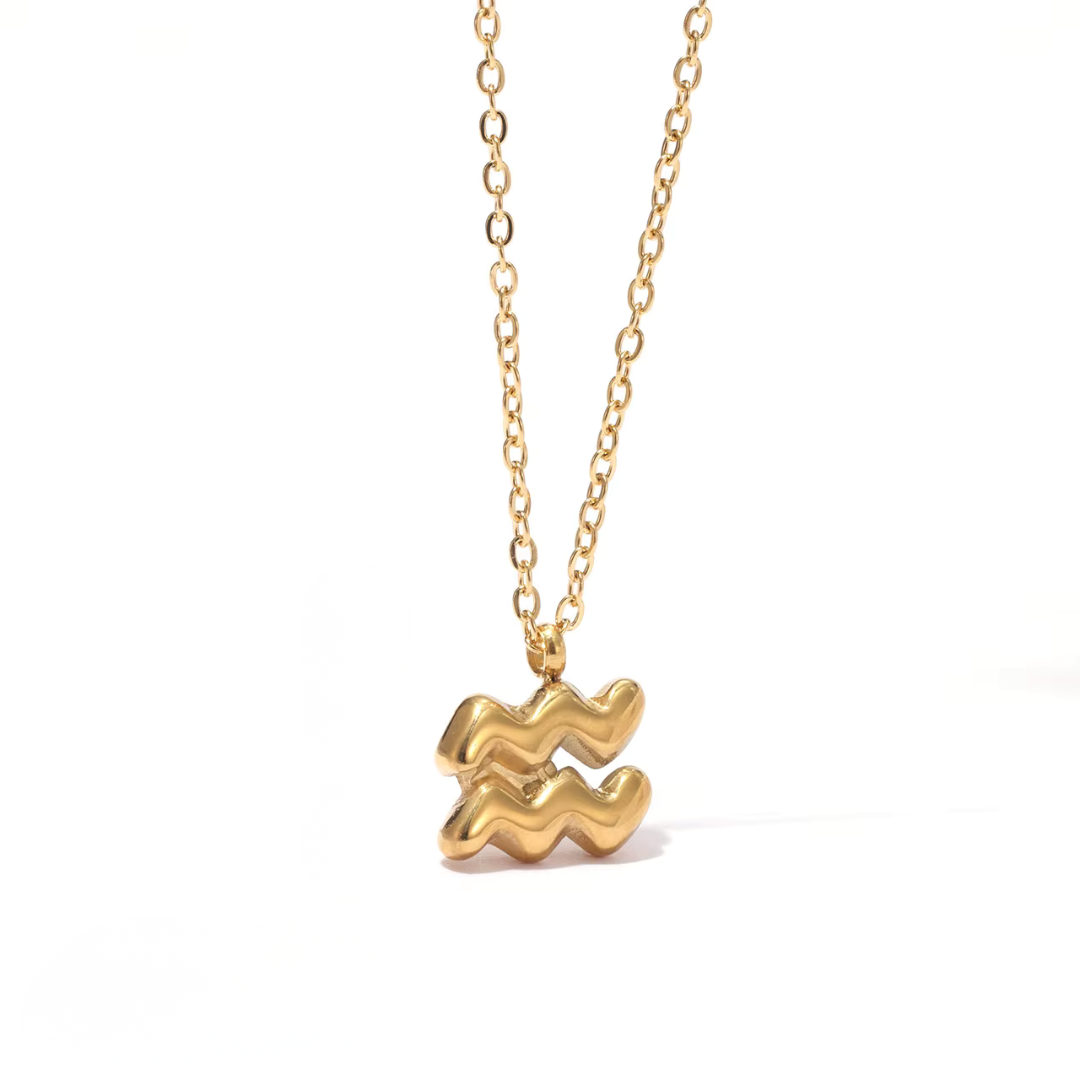 All 12 zodiac symbol bubble necklaces in 18K gold PVD displayed on a stone surface. Bold, chunky glyph pendants on delicate cable chains — waterproof and tarnish-free.
