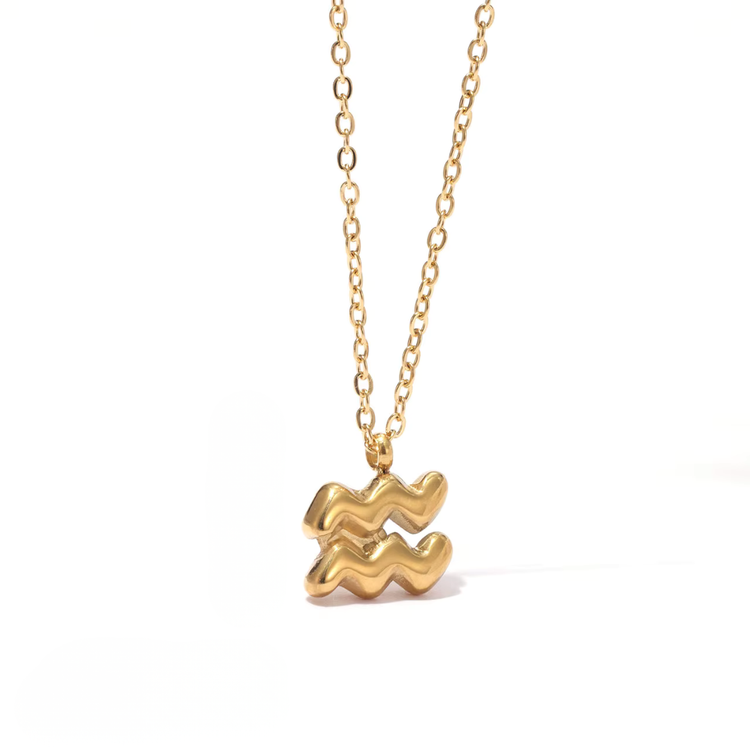 All 12 zodiac symbol bubble necklaces in 18K gold PVD displayed on a stone surface. Bold, chunky glyph pendants on delicate cable chains — waterproof and tarnish-free.