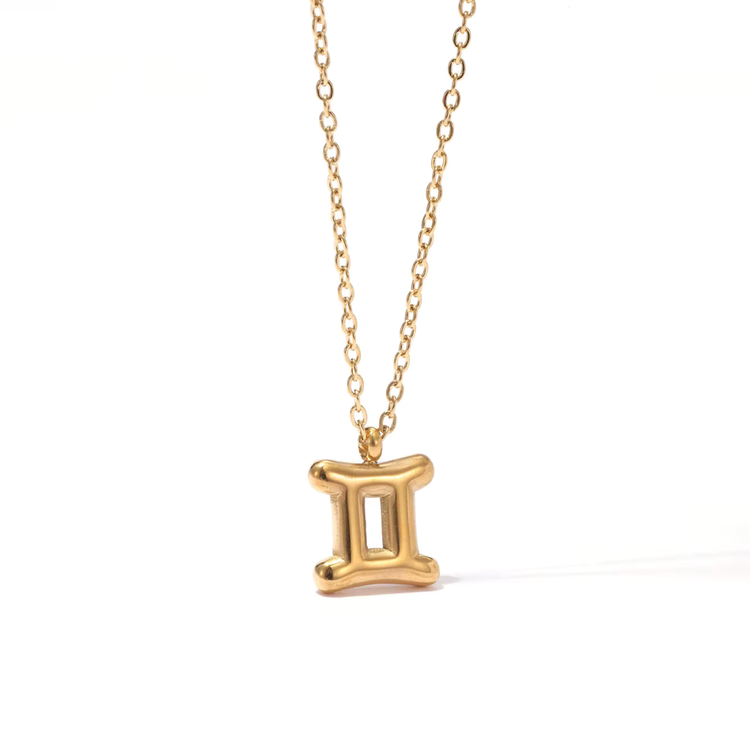 All 12 zodiac symbol bubble necklaces in 18K gold PVD displayed on a stone surface. Bold, chunky glyph pendants on delicate cable chains — waterproof and tarnish-free.