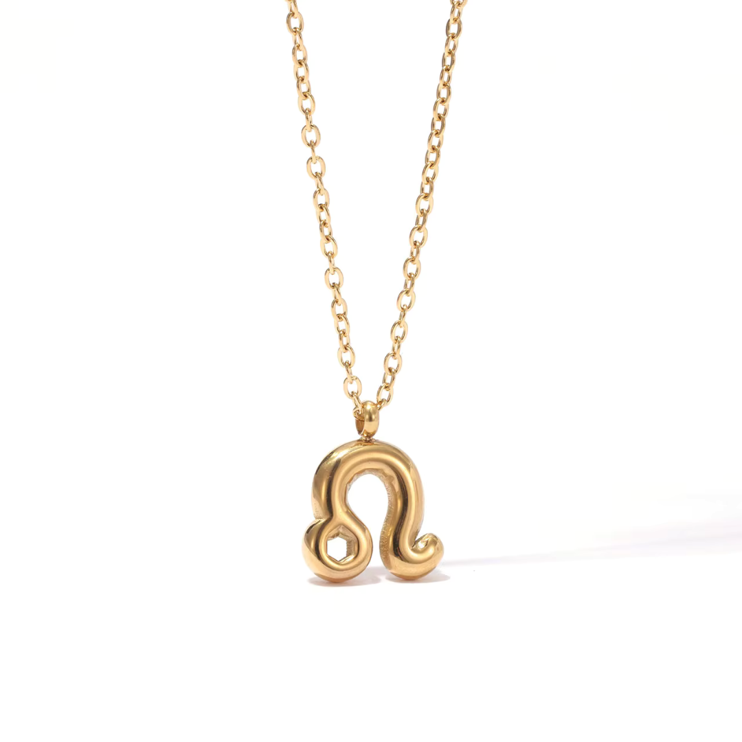 All 12 zodiac symbol bubble necklaces in 18K gold PVD displayed on a stone surface. Bold, chunky glyph pendants on delicate cable chains — waterproof and tarnish-free.